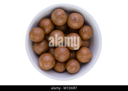 Schale mit frischem Macadamianüsse mit harten braunen Schalen gesehen von oben auf weißem isoliert und zentriert Stockfoto