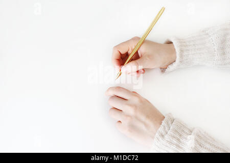 Woman's Hände in Pullover und Goldene balpoint Pens Schreiben, Zeichnen auf weißem Hintergrund. Bildung Konzept. Stock Bild gestaltet. Ansicht von oben, flach. Stockfoto