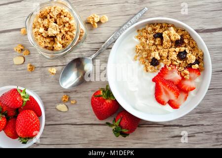 Joghurt mit Erdbeeren und Müsli. Tabelle Szene über einen Holz Hintergrund. Stockfoto