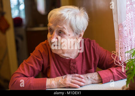 Eine ältere Frau, die am Tisch sitzen. Stockfoto