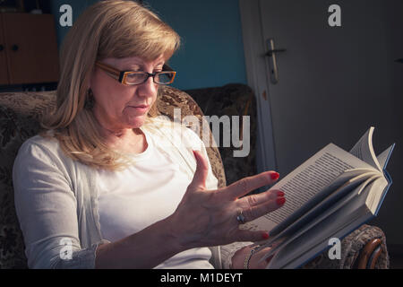 Ältere blonde Frau mit einem Buch Stockfoto