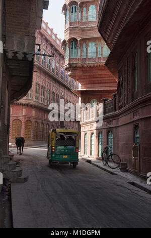 Kuh und Auto-rikscha vorbei vor der alten haveli Wohnungen, Bikaner, Rajasthan, Indien Stockfoto