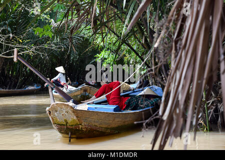 Ruderer ruhen im Boot im Delta des Mekong, Vietnam. Leuchtend rote Hose bieten große Gegensatz in der Wildnis von den grünen Dschungel Stockfoto