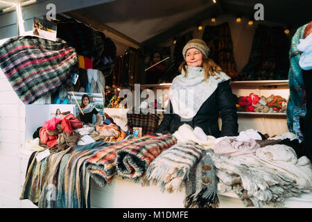 Helsinki, Finnland - 11. Dezember 2016: Frau Verkauf von Schals im Europäischen Winter Weihnachtsmarkt.