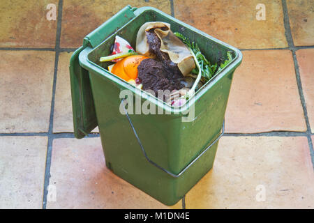 Eine grüne Kompost Ladeschaufel, mit organischen Abfällen Produkte wie Gemüse, Blumen, Kaffee und Teebeutel gefüllt Stockfoto