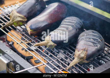 Aubergine auf Grill auf heiße Holzkohle und Feuer. Vorbereitung gesundes Essen im Urlaub. Kochen Gemüse auf Flammen. Leckeres Essen für Vegetarier Stockfoto