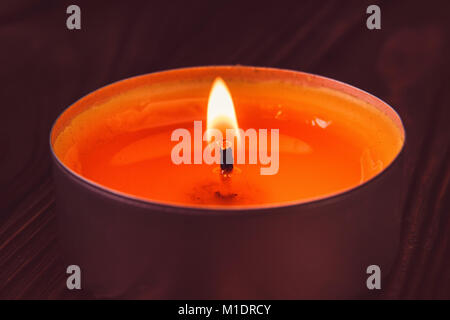 Kleine weiße Kerze brennt auf dunklem Hintergrund Stockfoto