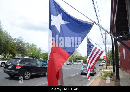 Die teaxs und Sterne und Streifen Fahnen hängen von einem Gebäude in Fredericksburg, Texas, USA Stockfoto