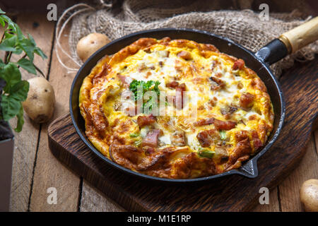 Französische omelette Savoyarde mit Speck, Käse und Lauch in eine Bratpfanne, rustikal Stockfoto