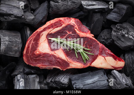 Rohe frische Fleisch Ribeye Steak auf schwarzer Kohle Hintergrund. Stockfoto