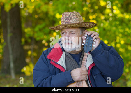 Outdoor Portrait von älteren Musiker mit Mandoline in herbstlicher Wald Ruhe Stockfoto