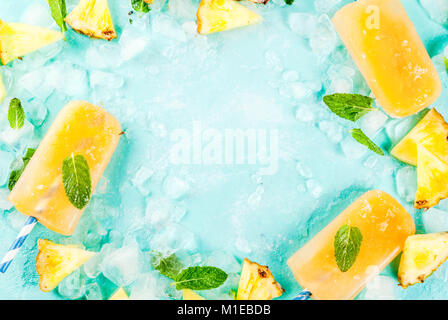 Hausgemachte Ananas Eis am Stiel auf Eis mit frischen Ananasscheiben und Minze, auf hellblauem Hintergrund Kopie Platz Top view Frame Stockfoto