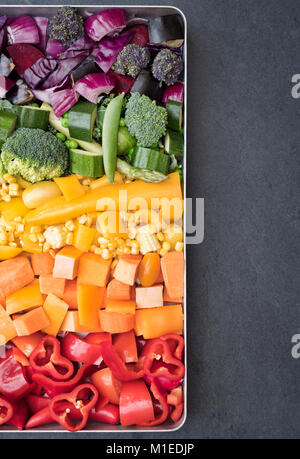 Schneiden bunte Gemüse in einem Backblech auf einer Schiefertafel Hintergrund Stockfoto