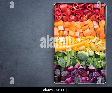 Schneiden bunte Gemüse in einem Backblech auf einer Schiefertafel Hintergrund Stockfoto