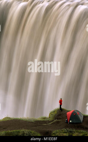 Island. Myvatn. Wasserfall Dettifoss. Touristen, stehende Frau von Zelt am Wasserfall. Stockfoto