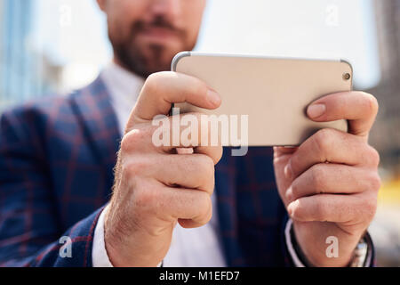 In der Nähe der Hände der Geschäftsmann mit seinem Smartphone Stockfoto