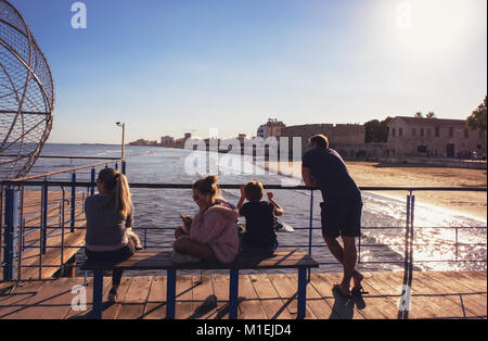 Larnaca, Zypern, 2. Januar 2018: Familie genießen Sie einen Tag am Meer beobachten die Wellen. Gelangweilte Teenager auf der Suche nach Telefon. LARNACA, 2. Januar 2018. Stockfoto