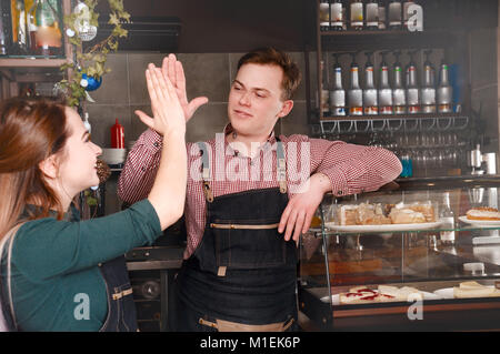 Gute Teamarbeit von zwei Barista am Arbeitsplatz. Schöner Mann und attraktive Frau macht Kaffee. Lebensmittel- und Getränkeindustrie Konzept Stockfoto