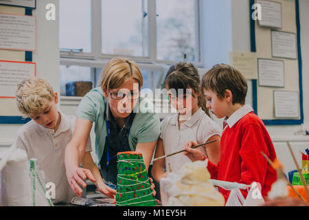 Grundschule Schüler arbeiten mit ihrer Lehrerin auf einer Wissenschaft Projekt im Klassenzimmer. Sie papiermache Vulkan. Stockfoto