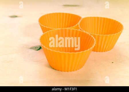 Orange Silikon Backformen für Muffins oder Cupcakes bei Massivholz Hintergrund. Stockfoto