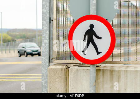 Ein rundes Schild was bedeutet 'keine Fußgänger erlaubt". Hält die Menschen gehen auf die Straße zu einem geschäftigen Flughafen Stockfoto