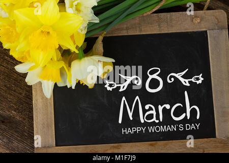 Frischer Frühling Narzissen Licht und Dunkel gelb, mit 8. März Grüße auf blackboard Stockfoto