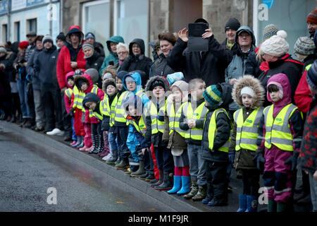 Schule Kinder aufpassen, als Mitglieder der Jarl Gruppe in Viking passt durch die Straßen marschieren in Lerwick auf Shetland Isles während der Up Helly Aa Wikinger Fest angezogen. Stockfoto