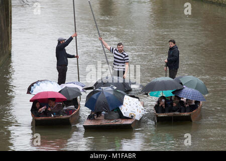 Touristen unter den Sonnenschirmen, während Sie stochern auf dem Fluss Cam in Cambridge, wie die sintflutartigen Regenfälle und starke Winde angekommen, wenn Sturm Georgina der Region getroffen. Stockfoto