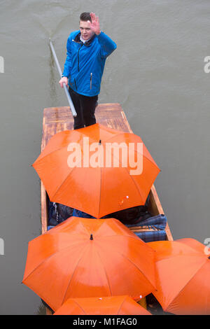 Touristen unter den Sonnenschirmen, während Sie stochern auf dem Fluss Cam in Cambridge, wie die sintflutartigen Regenfälle und starke Winde angekommen, wenn Sturm Georgina der Region getroffen. Stockfoto