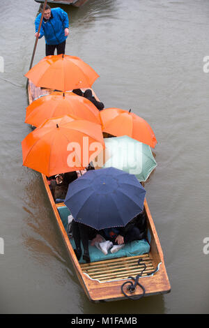 Touristen unter den Sonnenschirmen, während Sie stochern auf dem Fluss Cam in Cambridge, wie die sintflutartigen Regenfälle und starke Winde angekommen, wenn Sturm Georgina der Region getroffen. Stockfoto