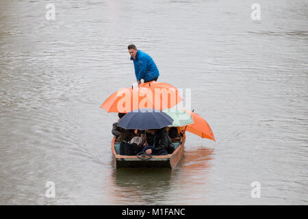 Touristen unter den Sonnenschirmen, während Sie stochern auf dem Fluss Cam in Cambridge, wie die sintflutartigen Regenfälle und starke Winde angekommen, wenn Sturm Georgina der Region getroffen. Stockfoto