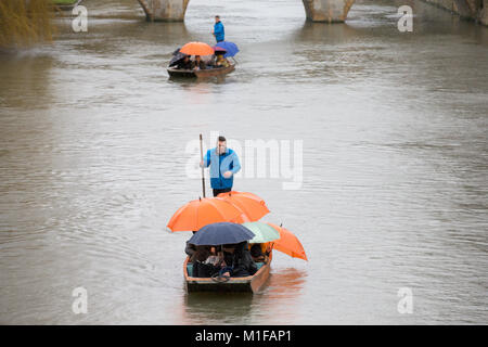 Touristen unter den Sonnenschirmen, während Sie stochern auf dem Fluss Cam in Cambridge, wie die sintflutartigen Regenfälle und starke Winde angekommen, wenn Sturm Georgina der Region getroffen. Stockfoto