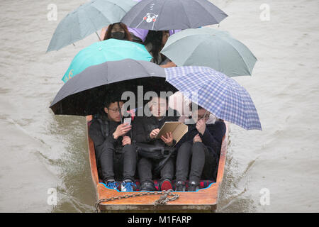 Touristen unter den Sonnenschirmen, während Sie stochern auf dem Fluss Cam in Cambridge, wie die sintflutartigen Regenfälle und starke Winde angekommen, wenn Sturm Georgina der Region getroffen. Stockfoto