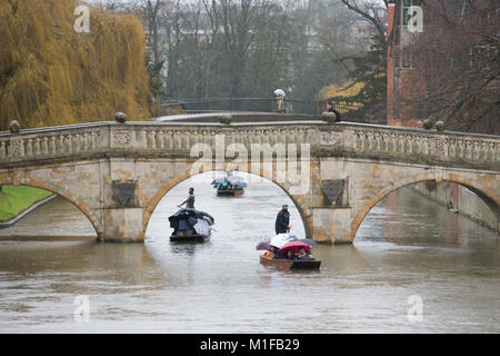 Touristen stochern auf dem Fluss Cam in Cambridge im Regen unter Regenschirmen Stockfoto