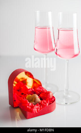 Schokolade Herzen in Rot heart-shaped Box, und zwei Gläser Champagner Rosé. weißen Hintergrund. Selektive konzentrieren. Stockfoto