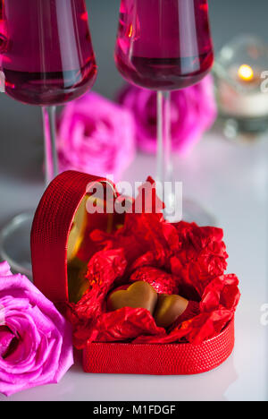 Schokolade Herzen in Rot heart-shaped Box, rose Blumen, zwei Gläser Champagner und eine Kerze. Selektive konzentrieren. Stockfoto