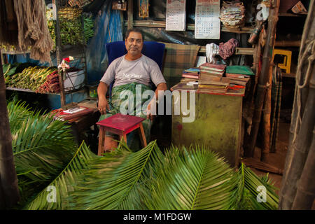 Palm Verkäufer in seinem Stall, das verdoppelt, wie sein Büro, am Mullick Ghat Blumenmarkt in Kalkutta/Kolkata, West Bengal, Indien sitzen Stockfoto