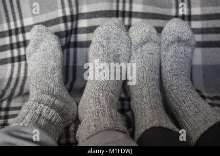 Füße von Paar in Wollsocken auf der karierten Decke, Wohnkomfort und liebe Konzept Stockfoto