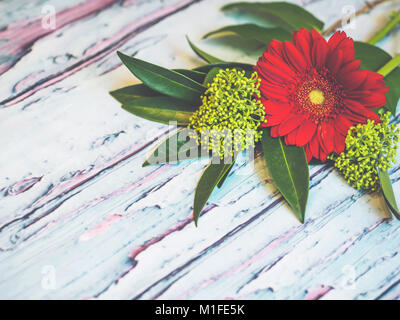 Ein Bouquet von roten und grünen Blumen liegen auf einem Bläulichen rustikalen Holztisch Schuß gegen weiche - fokussierte Hintergrund. Stockfoto