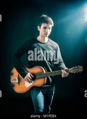 Portrait von hipster junger Mann oder jugendlich Gitarre spielen auf schwarzem Hintergrund, im Studio shot Stockfoto