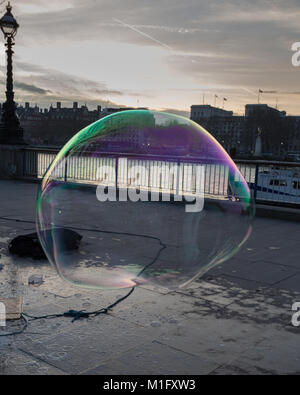 South Bank, London, UK. 30 Jan, 2018. Jake, ein Bubble Maker oder Bubbler als er bevorzugt genannt zu werden, unterhält auf der Londoner South Bank mit großen, leuchtend farbige Blasen wie die Sonne über der Themse, London Eye, Westminster und South Bank setzt. Credit: Imageplotter Nachrichten und Sport/Alamy leben Nachrichten Stockfoto