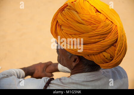 Blick auf indischen Mann von hinten mit Sonne auf seinem goldenen Safran Turban in Pushkar Camel Fair, Rajasthan, Indien Stockfoto