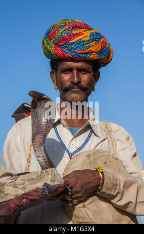 Schlangenbeschwörer mit einer Cobra Touristen für Geld an die Pushkar Camel Fair, Rajasthan, Indien zu unterhalten Stockfoto