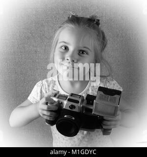 Die fröhliche kleine Mädchen der Fotograf mit der Kamera in den Händen. Es ist die aus einer alten Schwarzweiß-Foto stilisierte Stockfoto