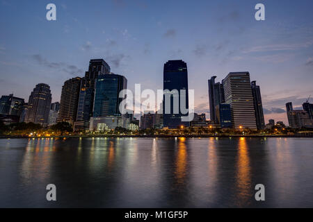 Blick auf die modernen Wolkenkratzer hinter See an der Benjakiti (benjakitti) Park in Bangkok, Thailand, im Morgengrauen. Stockfoto