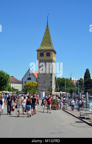 Waterfront im Hafen von Lindau am Bodensee mit Menschen und der alte Leuchtturm als Mangturm - Deutschland bekannt. Stockfoto