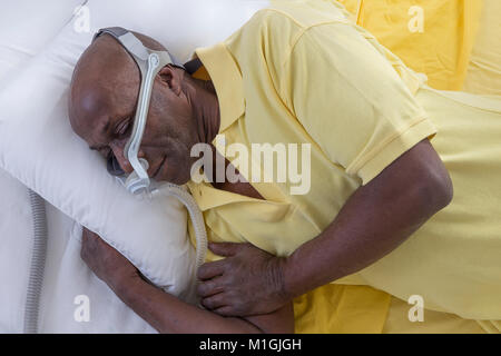 Healthcare Konzept, afrikanischen, amerikanischen Mann mit obstruktiver Schlafapnoe gut schlafen mit CPAP-Gerät, Mann im Bett tragen CPAP-Maske, auf weißem Hintergrund Stockfoto