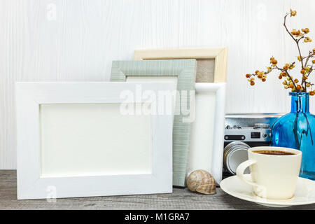 Satz von leeren Fotorahmen auf hölzernen Schreibtisch. Tasse Kaffee im Vordergrund. Stockfoto