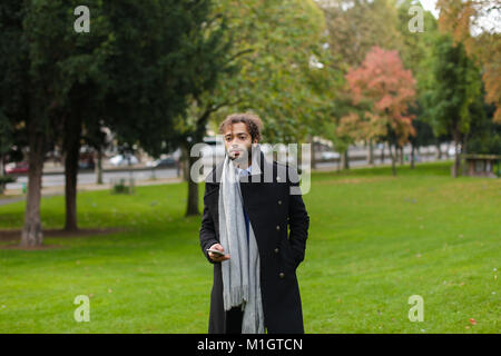 Hispanic Mann chatten mit Freundin auf dem Smartphone im Park. Stockfoto