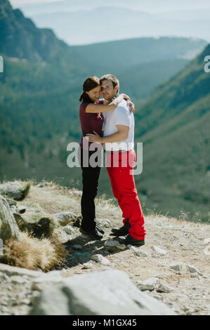 Mann und Frau in Liebe umarmen einander und genießen die Aussicht auf die Berge. Stockfoto